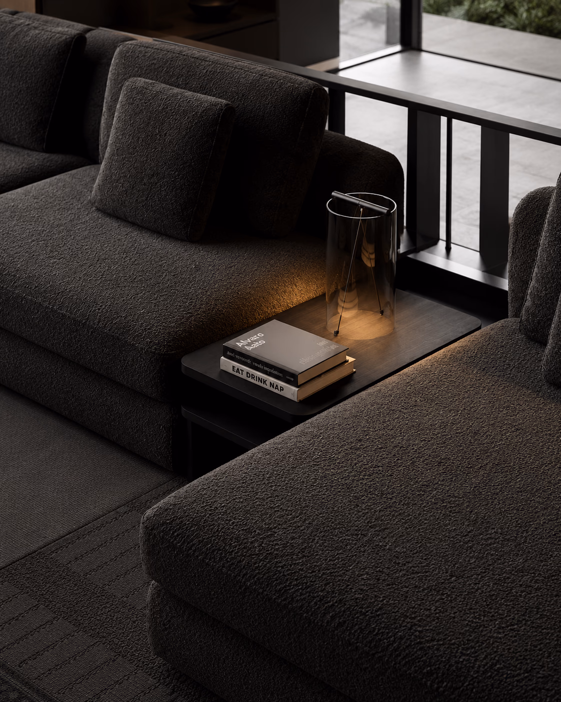Dark sofa with a side table, books and a glass lamp